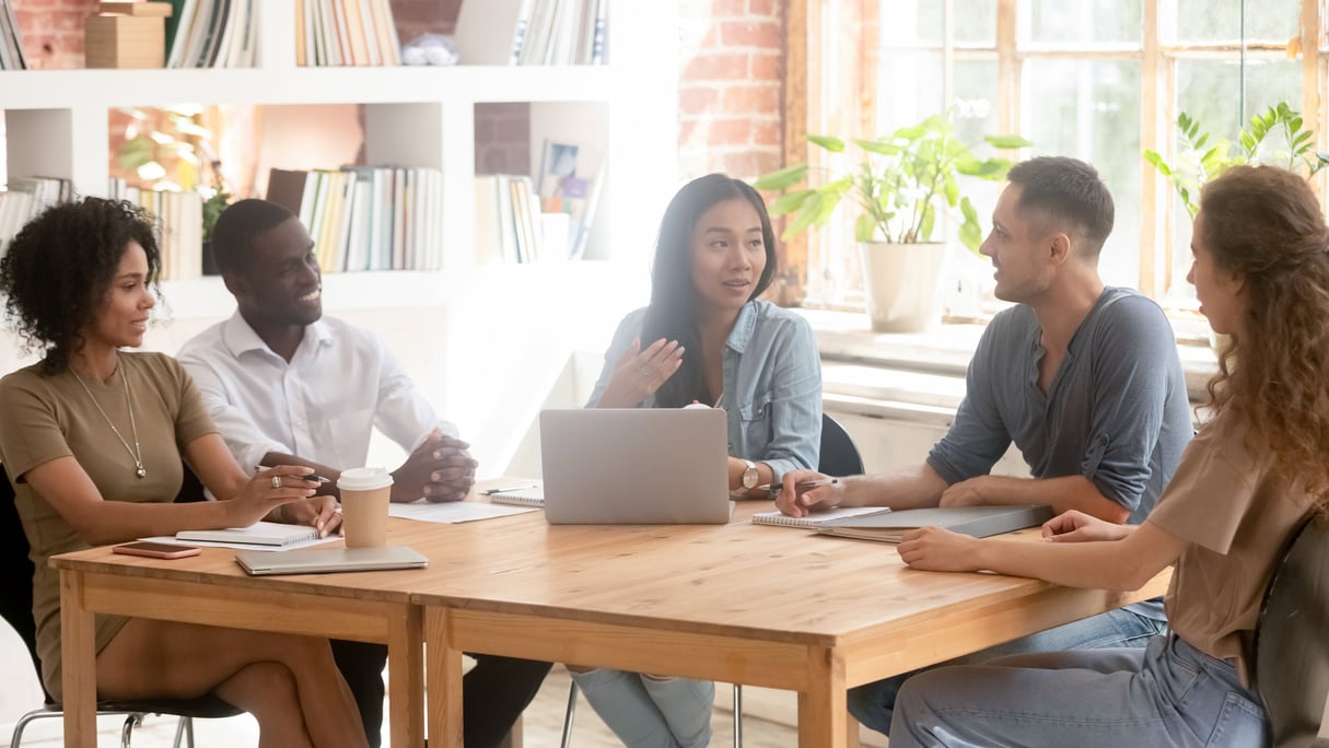 Asian creative leader speaking at diverse team office meeting