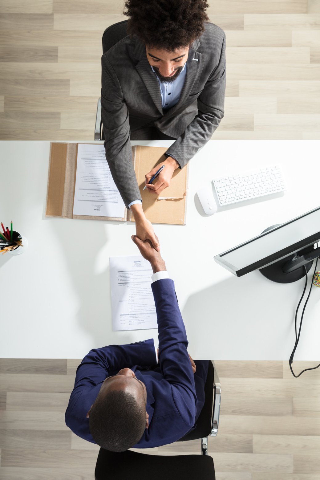 Young Businessman Shaking Hand With Candidate Over White Desk